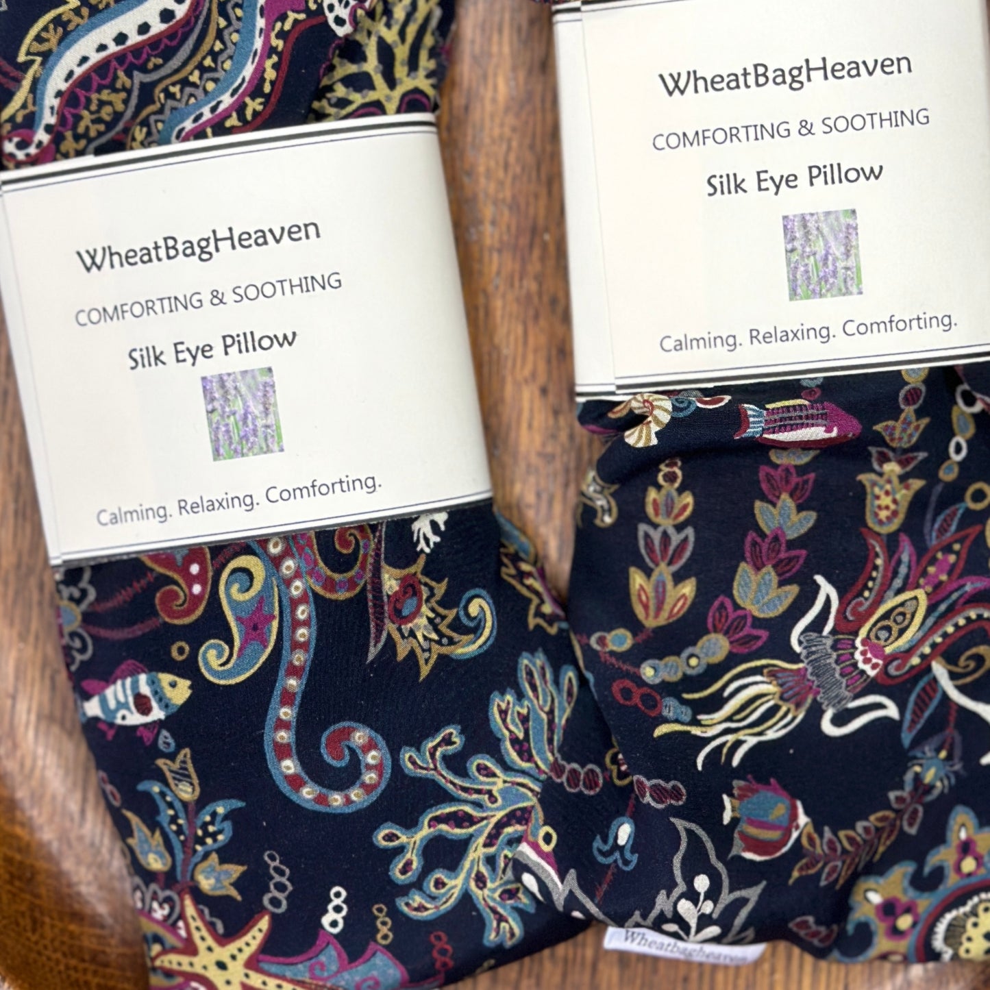 Two lovey silk lavender eye pillows in an under the ocean print on navy blue background with makers tags and labels
