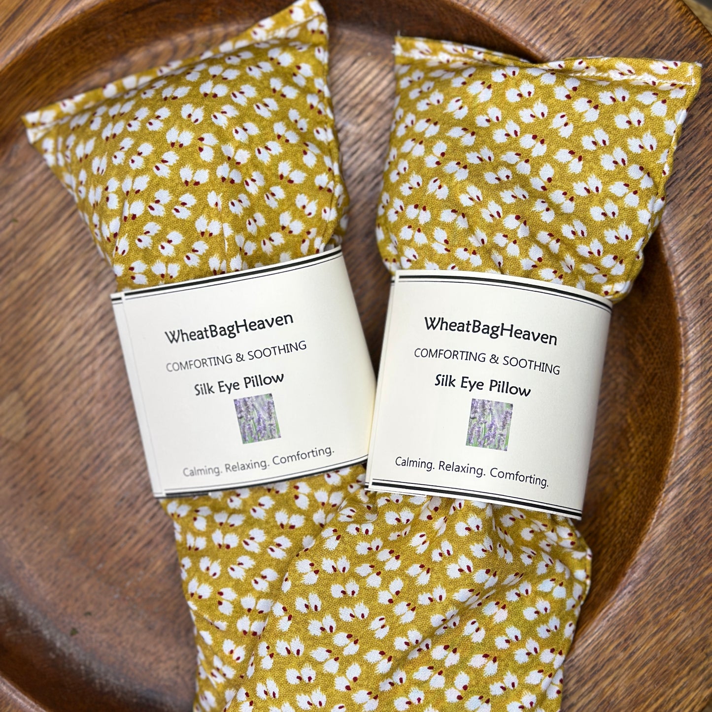 Silk small ochre floral printed eye pillows side by side on wooden tray handcrafted by wheatbagheaven.com