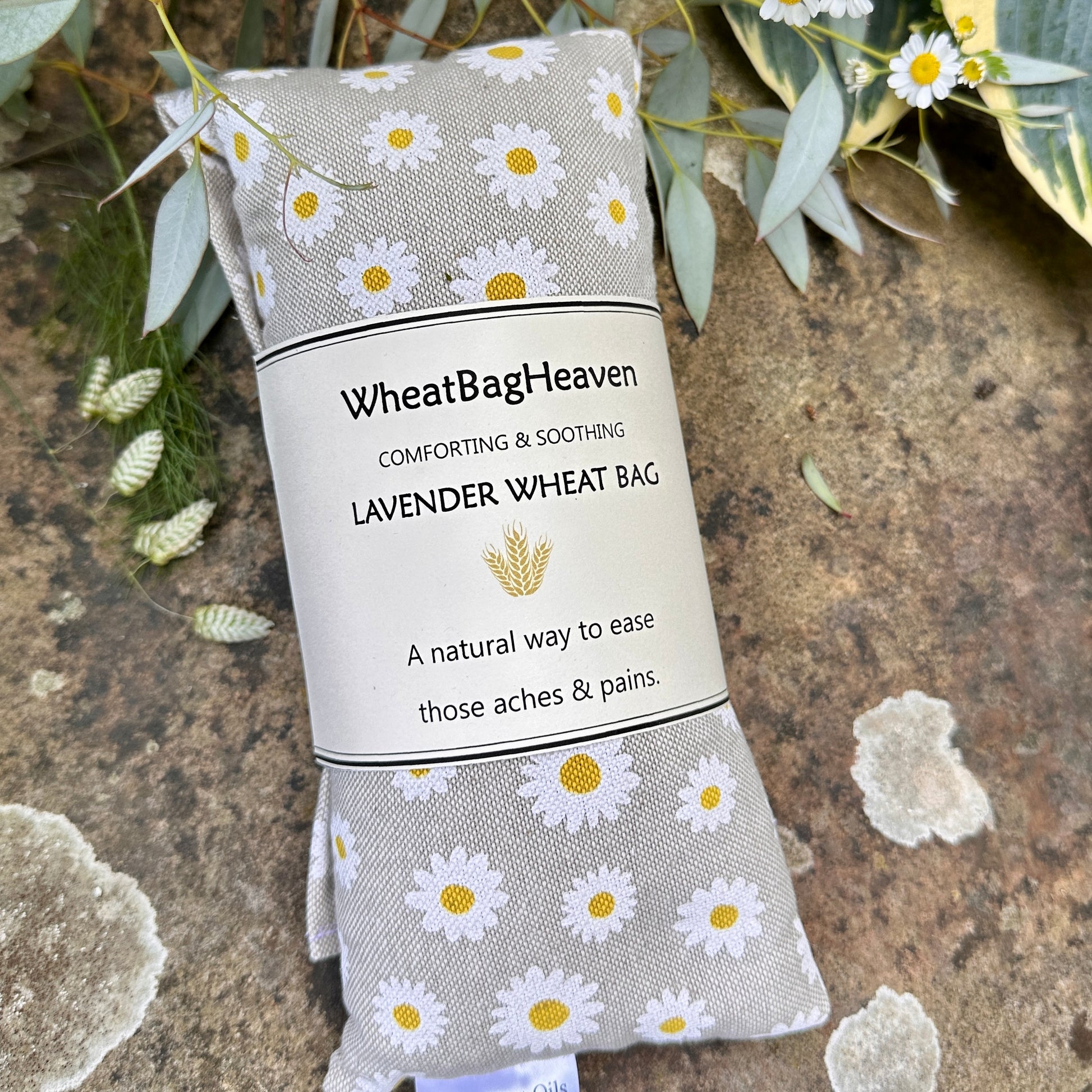 Daisy print on beige background, lavender scented long wheat bag with stone backdrop in the garden at WheatBagHeaven 