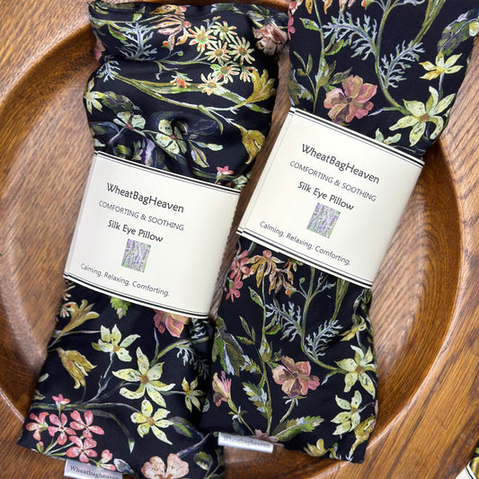 Two lovely floral silk eye pillows side by side on a wooden tray use in yoga meditation and relaxation