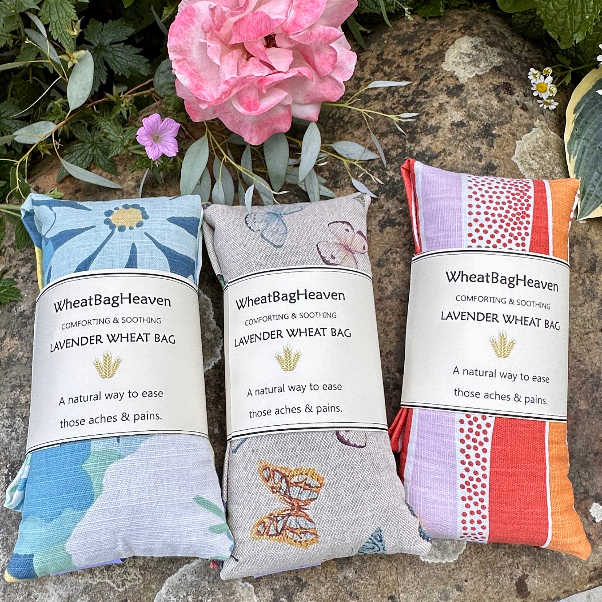 Three in a row lavender scented long wheat bag heat pads. From left to right Zumba blue/yellow florals, then butterflies on a beige background and lastly zesty orange wave pattern which has pinks and white colour way, all cotton fabric