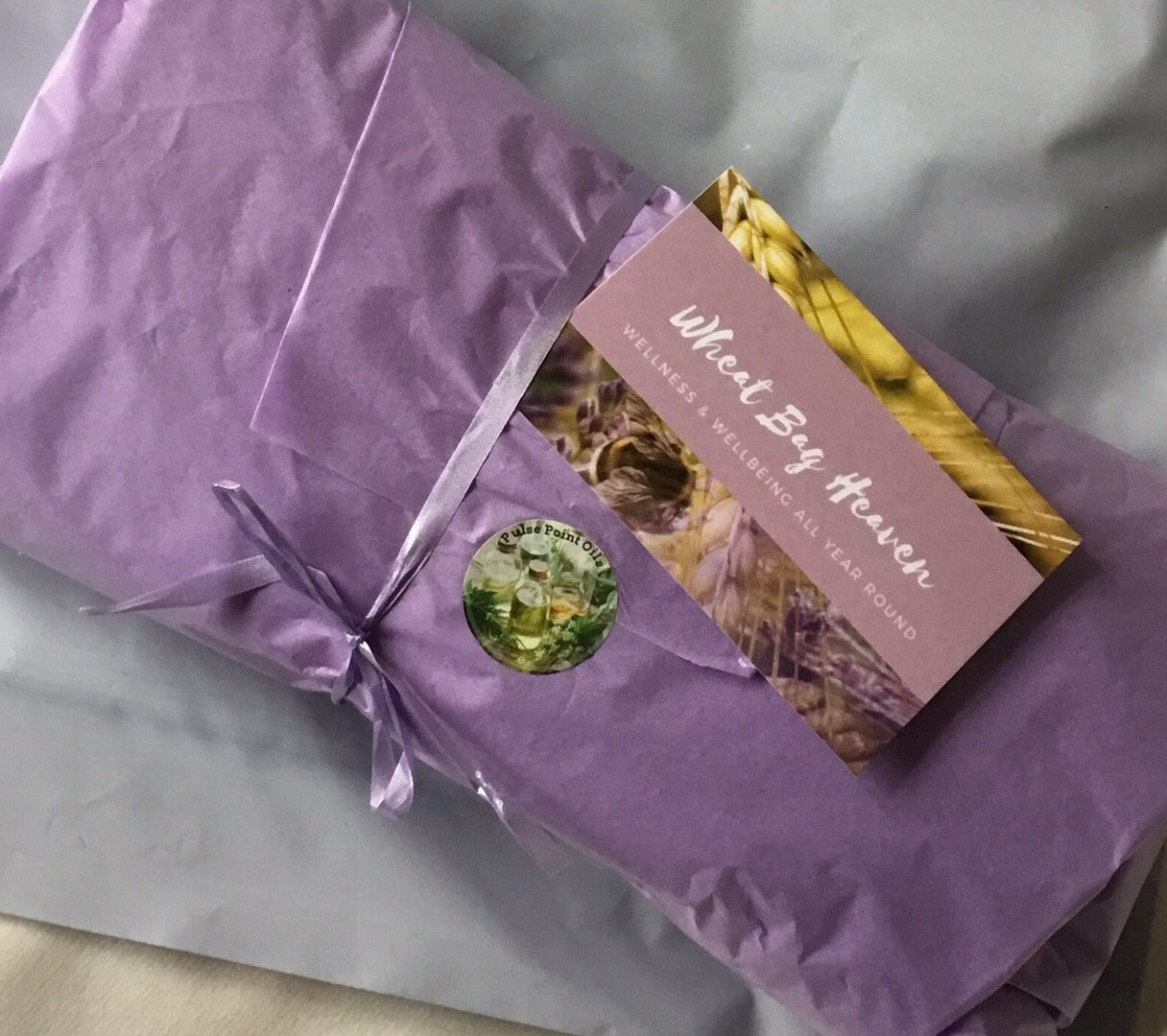 handmade lavender wheat bag wrapped in purple tissue paper tied with ribbon ready to post wellness gift