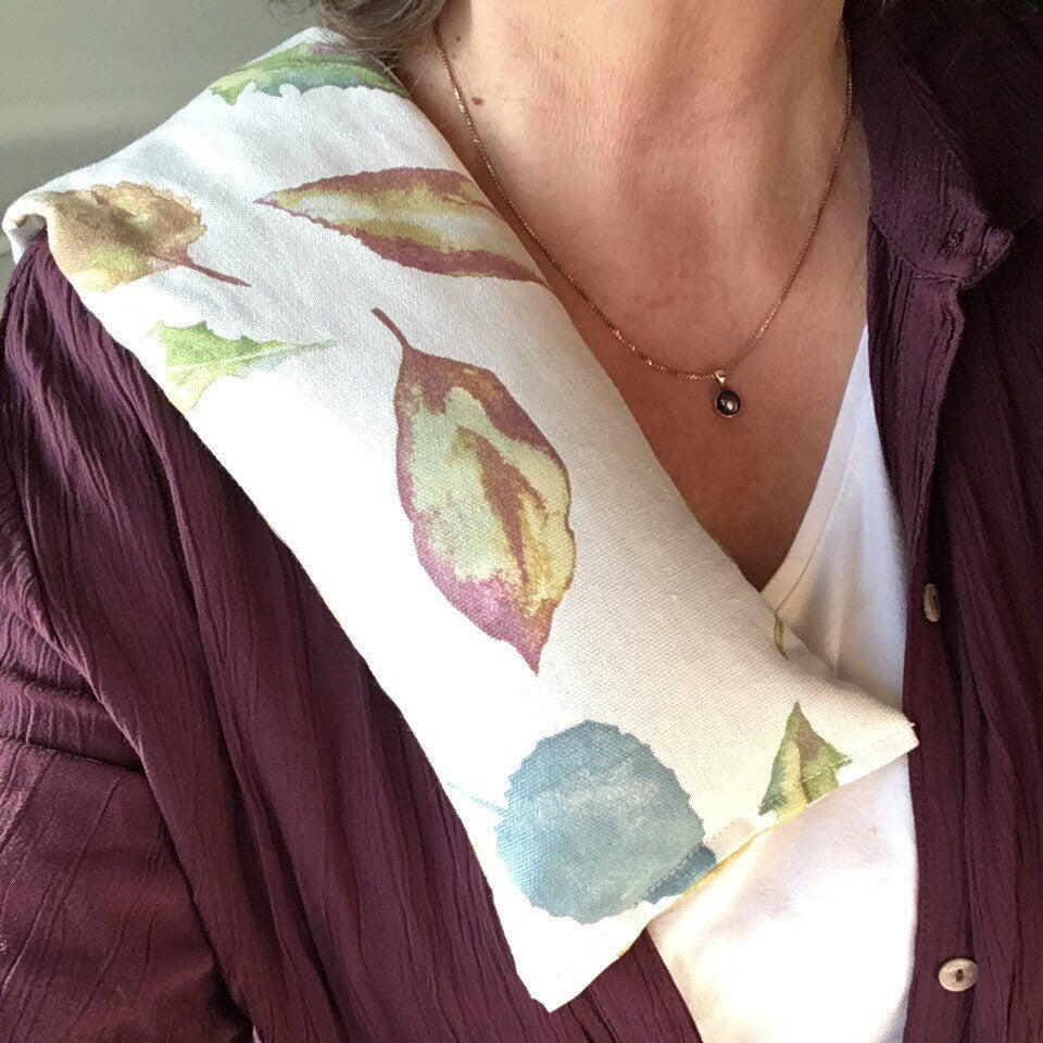 Woman using a Long lavender scented wheat bag in botanical multi coloured leaf print called Falling Leaves