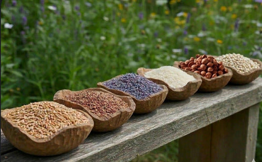 six bowls lined up on a wooden bench each filled with heat, barley, lavender, cherry stones, flax seed and rice. Natural ingredients used to fill up heat packs