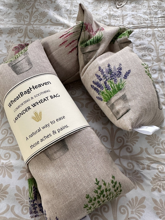 Lavender wheat bags with an all over pot plant print including alliums, lavender, salvia, basil on a beige base. The label reads WheatBagHeaven comforting and soothing Lavender Wheat Bag a natural way to ease those aches and pains 