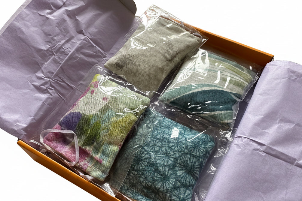 Packaged 4 pocket hugs  in a lilac tissue paper lined box. Each lavender sachet is individually packaged with clear wrap in a yellow postal box on a white background