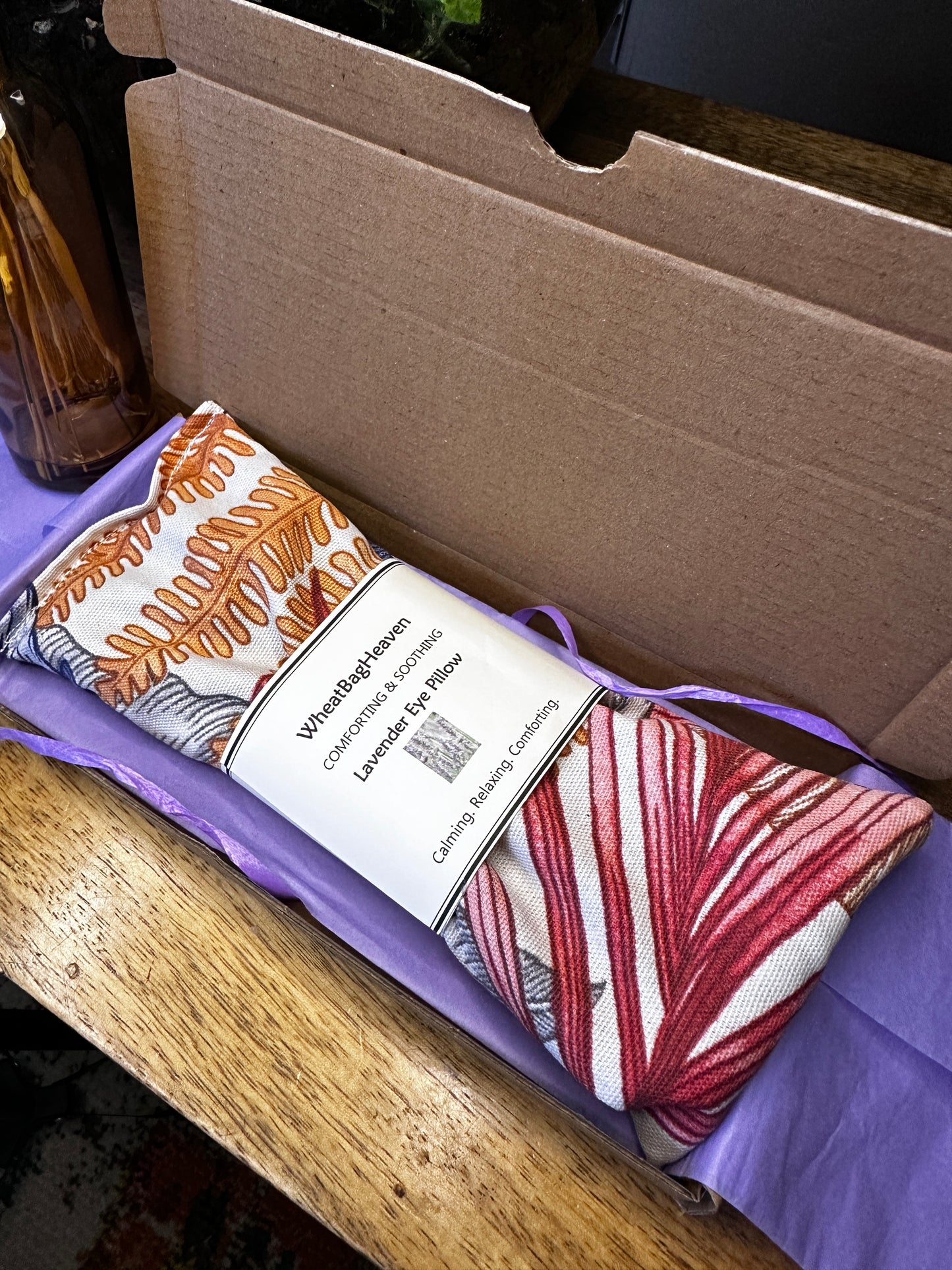 Flax seed eye pillow in Maldives orange botanical print in a letterbox sized gift box with lilac tissue paper 