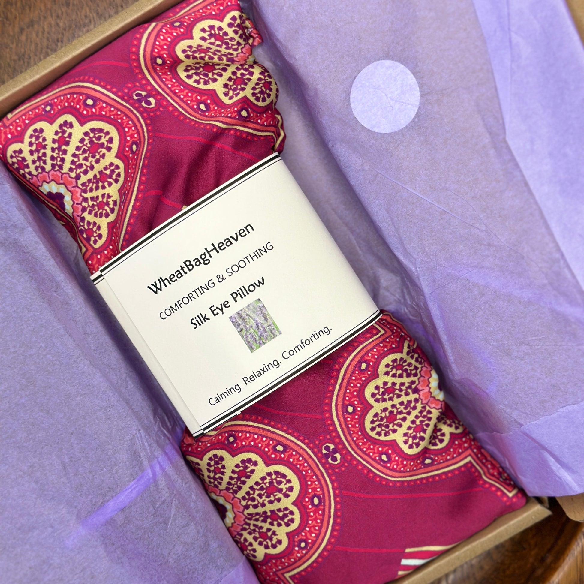reiki lavender scented silk eye pillow in a pink, orange and gold art deco print on lilac tissue in postal box