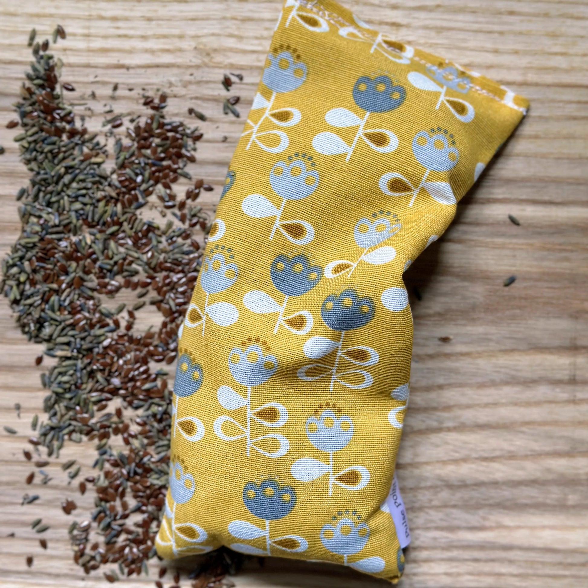 eye pillow sleep mask in a bright yellow floral fabric with filling of flaxseed and lavender buds