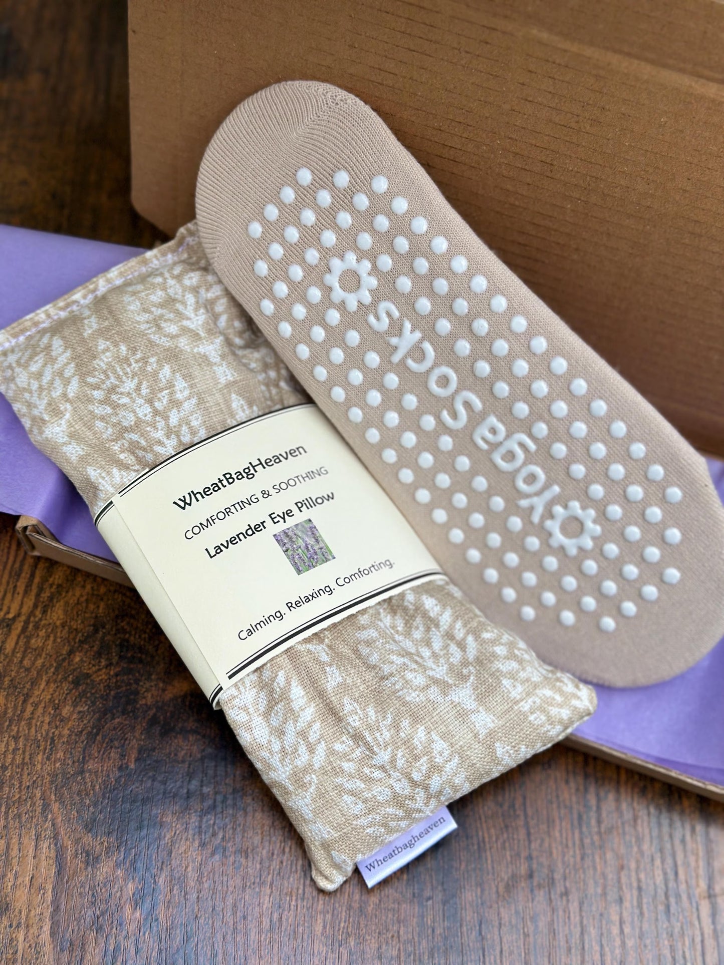 Beige Yoga socks and an eye pillow in cream and beige botanical print on a wooden surface