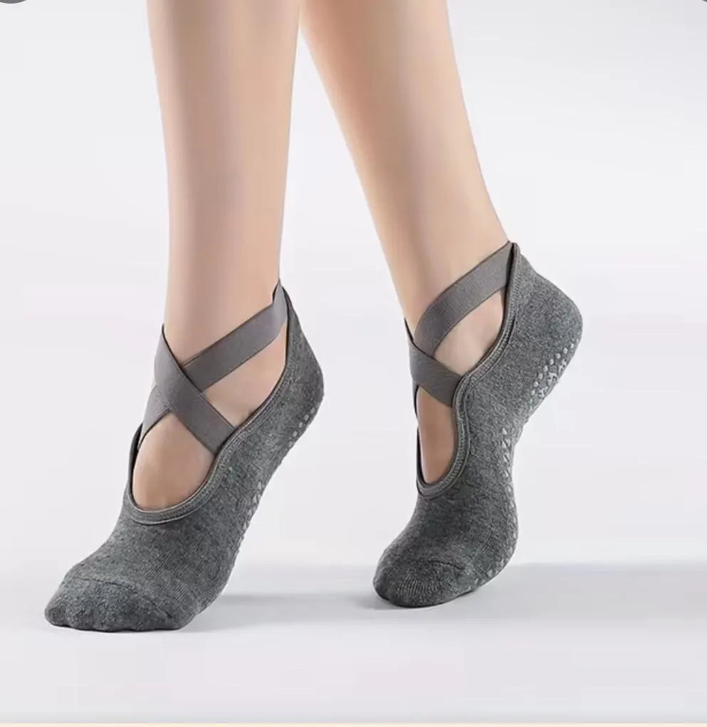 Gray yoga, pilates, barre socks with criss-cross straps on a white background