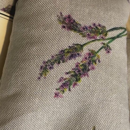 short video of Two Wheat bags with a lavender flower print design on a wooden surface. One wheat bag has maker's belly band that read WheatBagHeaven comforting and soothing Lavender Wheat Bag A natural way to ease those aches and pains. Both have makers tags