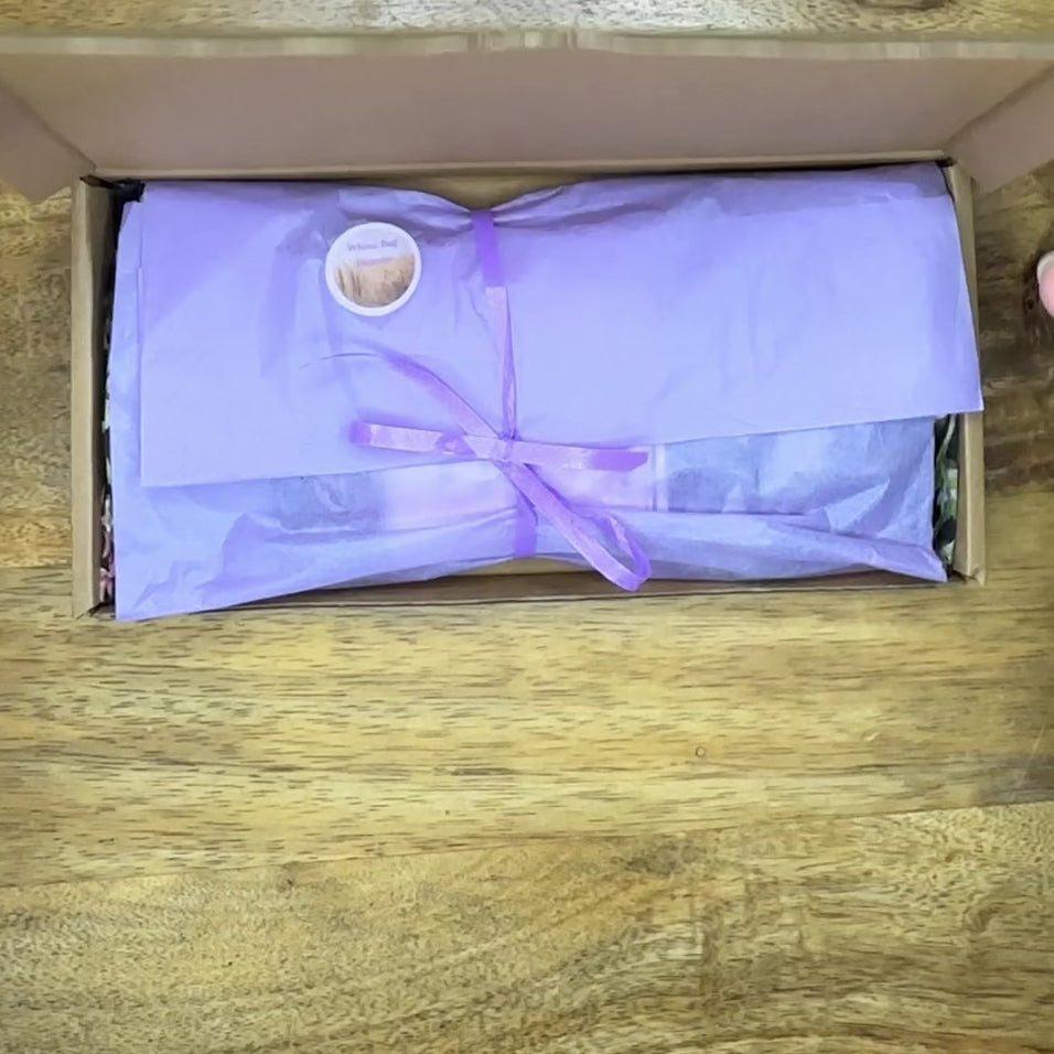 Unpacking video of wheatbagheaven’s black silk floral eye pillow wrapped in tissue tied with ribbon and filled with flax seed and lavender buds